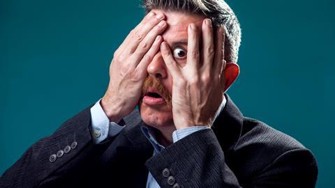 scared worried business man hide behind fingers