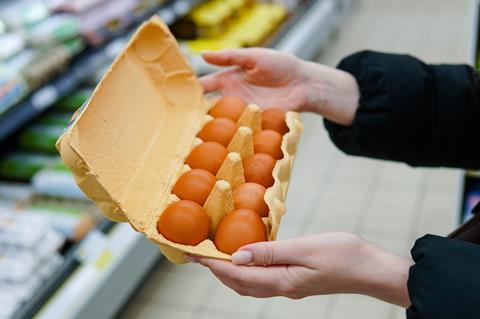 Woman chooses chicken eggs in a grocery store. Close up - Getty Images