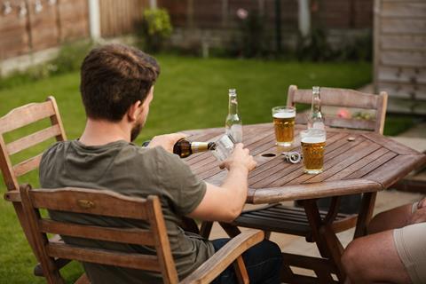 Man pours beer into glass at garden table