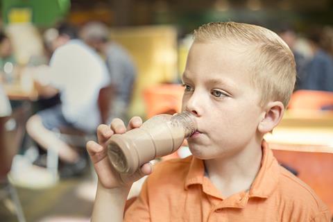 A picture of a young boy drinking a milkshake out of a bottle