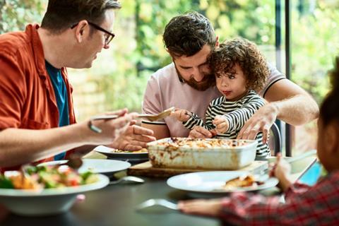 toddler eating vegan lunch with family gay family meal time dinner - GettyImages-1217375362 (1)