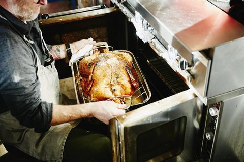 Man pulling cooked turkey out of oven - stock photo - Getty Images