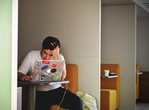 Bored or annoyed young man working on a laptop