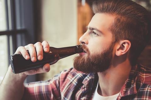 Bearded hipster drinking from a beer bottle