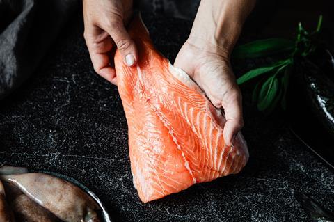 Close-up of a chef preparing fresh salmon fillet in kitchen