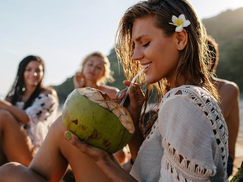 Young woman drinking coconut water from a coconut 
