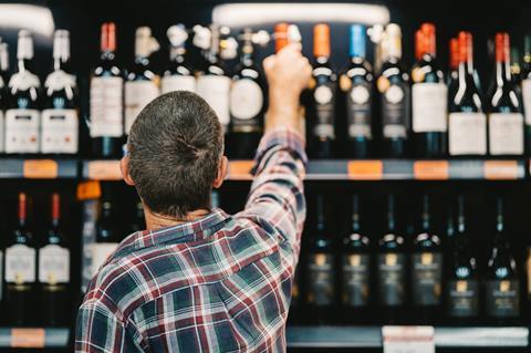 Man choosing bottle of tine in supermarket