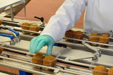 Factory worker on scotch egg processing line