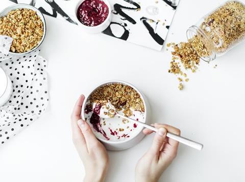 Person putting granola into a breakfast bowl