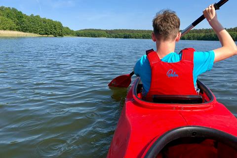 Red canoe being paddled away on a lake