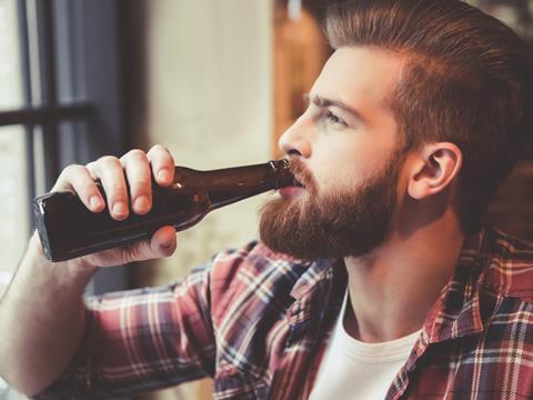 Bearded hipster drinking from a beer bottle